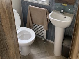 A bathroom with a toilet, sink, towel, radiator, and trash can at WW15 Plot Newquay
