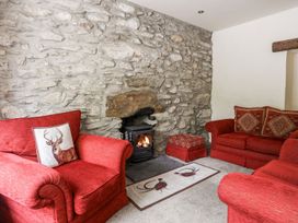 A living room with a fireplace and red sofas at Llys Elen in Caernarfon