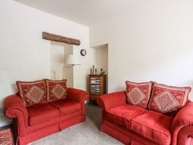 A living room with red sofas and a cabinet at Llys Elen in Caernarfon