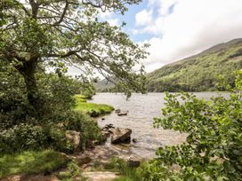 A scenic view of a lake with trees and rocks at Llys Elen in Caernarfon