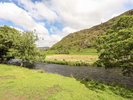 A river with grass and trees beside it at Llys Elen in Caernarfon