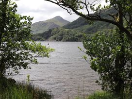 A view of a lake with trees and mountains at Llys Elen in Caernarfon