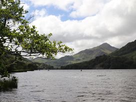 A view of a lake with mountains and trees in the background at Llys Elen Caernarfon