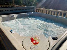 A hot tub with water and a glass of drink at Owls House - White Cross Bay in Windermere