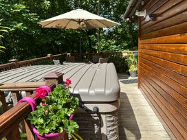 An outdoor area with a hot tub and a wooden deck at Owls House - White Cross Bay Windermere