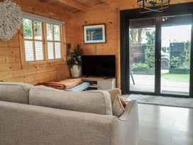 A living room with a sofa and television at Caban Tan Y Dderwen in Chwilog