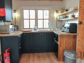 A kitchen with a sink and shelves at Caban Tan Y Dderwen in Chwilog