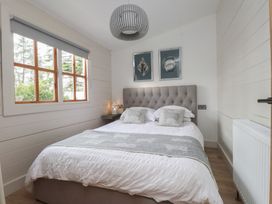 A bedroom with a bed and wall art at Caban Tan Y Dderwen in Chwilog