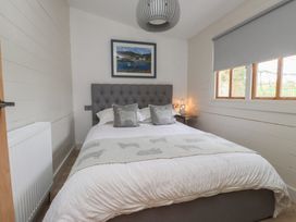 A bedroom with a bed and bedside lamp at Caban Tan Y Dderwen in Chwilog
