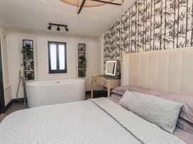 A bathroom with a bathtub and a mirror at Caban Tan Y Ffawydd in Chwilog near Y Ffor