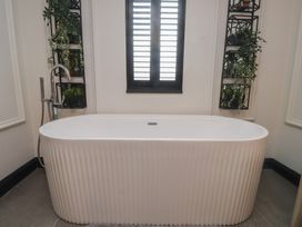 A bathroom with a bathtub and plants on a shelf at Caban Tan Y Ffawydd in Chwilog near Y Ffor