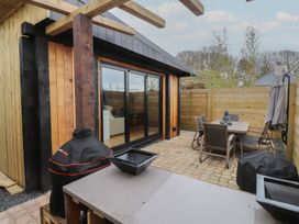 An outdoor area with a table and chairs beside a building at Riverside Lodge Afonwen