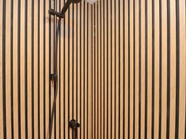 A bathroom with wooden striped wall and shower fittings at Riverside Lodge Afonwen