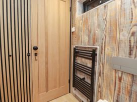 A bathroom with a door and a heating rail at Riverside Lodge Afonwen