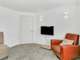 A living room with a TV and a chair at 40 Raleigh Court Sherborne