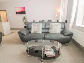 A living room with a sofa, coffee table, and plant at The Sea Chest in Alnmouth