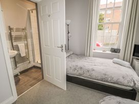 A bedroom with a bed, lamp and bathroom door at The Sea Chest in Alnmouth