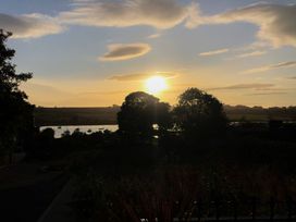 A sunset view with trees and water at The Sea Chest in Alnmouth