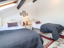 A bedroom with two beds and a lamp at Englewood Cottage in Hexham