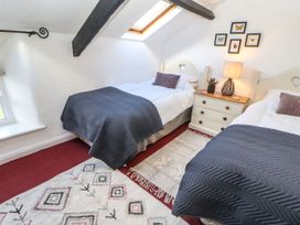 A bedroom with two beds, a nightstand, and a window at Englewood Cottage in Hexham