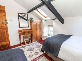 A bedroom with a bed, mirror, and wooden furniture at Englewood Cottage Hexham