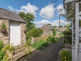 A pathway with stone buildings and garden plants at Englewood Cottage in Allenheads