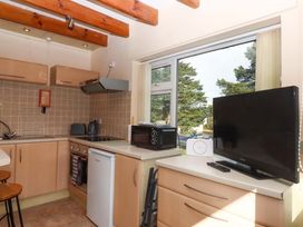A kitchen with cabinets, stove, television, and microwave at Flat 1 Lee Cliff Park in Dawlish Warren