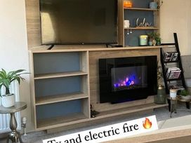 A living room with a TV and electric fire at 52 Juniper Close, Exmouth
