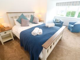 A bedroom with a bed and chairs at Rosevale Villa in St Ives