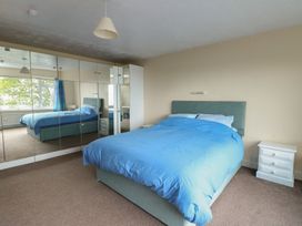 A bedroom with a bed and mirror wardrobe at Bryn Y Felin in Y Felinheli