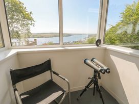 A conservatory with a telescope and chair at Bryn Y Felin in Y Felinheli