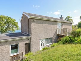 A house with a deck next to grass and trees at Bryn Y Felin in Y Felinheli