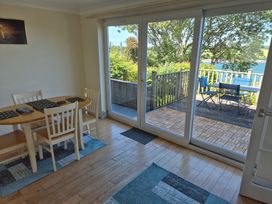 A dining room with a table and chairs overlooking a deck at Bryn Y Felin Y Felinheli