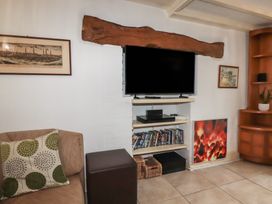 A living room with a TV and shelf at Plenteth in Truro