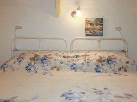 A bed with floral bedding and wall light at Plenteth in Truro