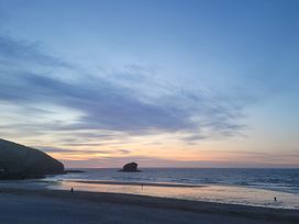 A beach scene with a rock and people at 16 Forth An Nance Portreath