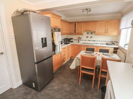 A kitchen with a refrigerator, stove, and dining table at 16 Forth An Nance Portreath