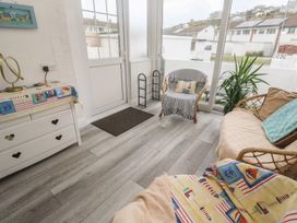 A conservatory with a sofa and chair at 16 Forth An Nance in Portreath