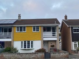 A house with yellow exterior and solar panels at 16 Forth An Nance in Portreath