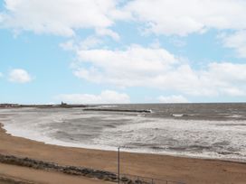 A beach with waves and a pier at 55 Meldon terrace in Newbiggin-by-the-Sea