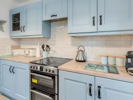 A kitchen with blue cabinets and appliances at Bay Tree Cottage Heacham