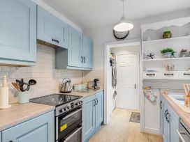 A kitchen with blue cabinets and appliances at Bay Tree Cottage in Heacham