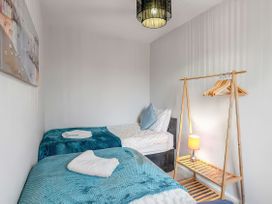 A bedroom with two beds and a clothes rack at Bay Tree Cottage in Heacham