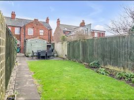 A garden with grass and a patio area at Bay Tree Cottage in Heacham