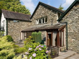 An outdoor view of a stone house with a patio and garden at The Gallery in Windermere