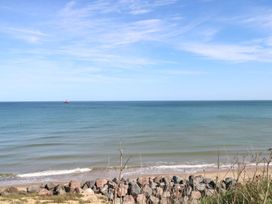 A view of the ocean with a boat in the distance and rocks at the shore