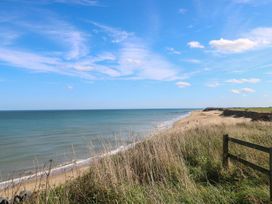 A beach with grass and an ocean view at The Ivy in Norwich