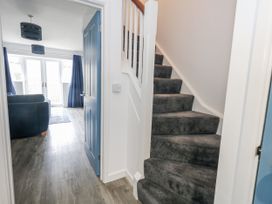 A hallway with a staircase and a view into a living room at 8 Park View Grove, Weymouth