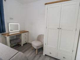 A bedroom with wardrobe, mirror, and vanity desk at 8 Park View Grove in Weymouth
