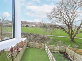A garden view with a tree and grass area at 8 Park View Grove in Weymouth